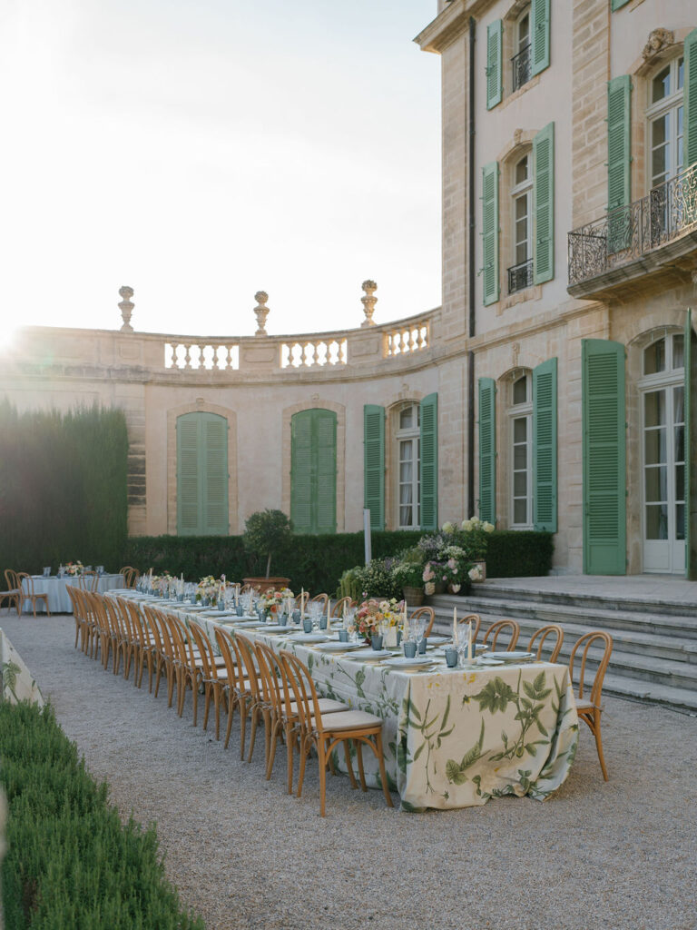 Long banquet table set in a chateau courtyard for an editorial Provence wedding designed by a wedding planner France.