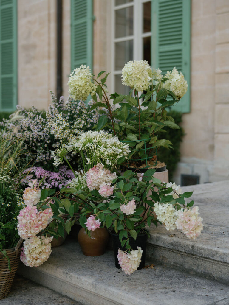 Floral arrangements placed on stone steps of a Provence chateau as part of an editorial wedding design.
