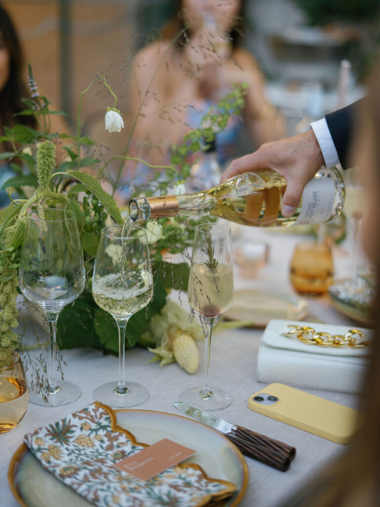 Champagne being poured at a long dinner table during an editorial Provence wedding reception.