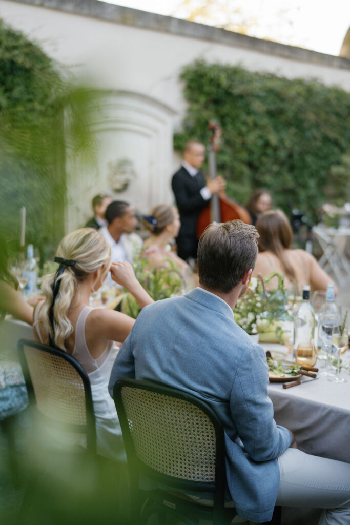 Guests seated for an outdoor dinner while live music plays during a Provence wedding evening.