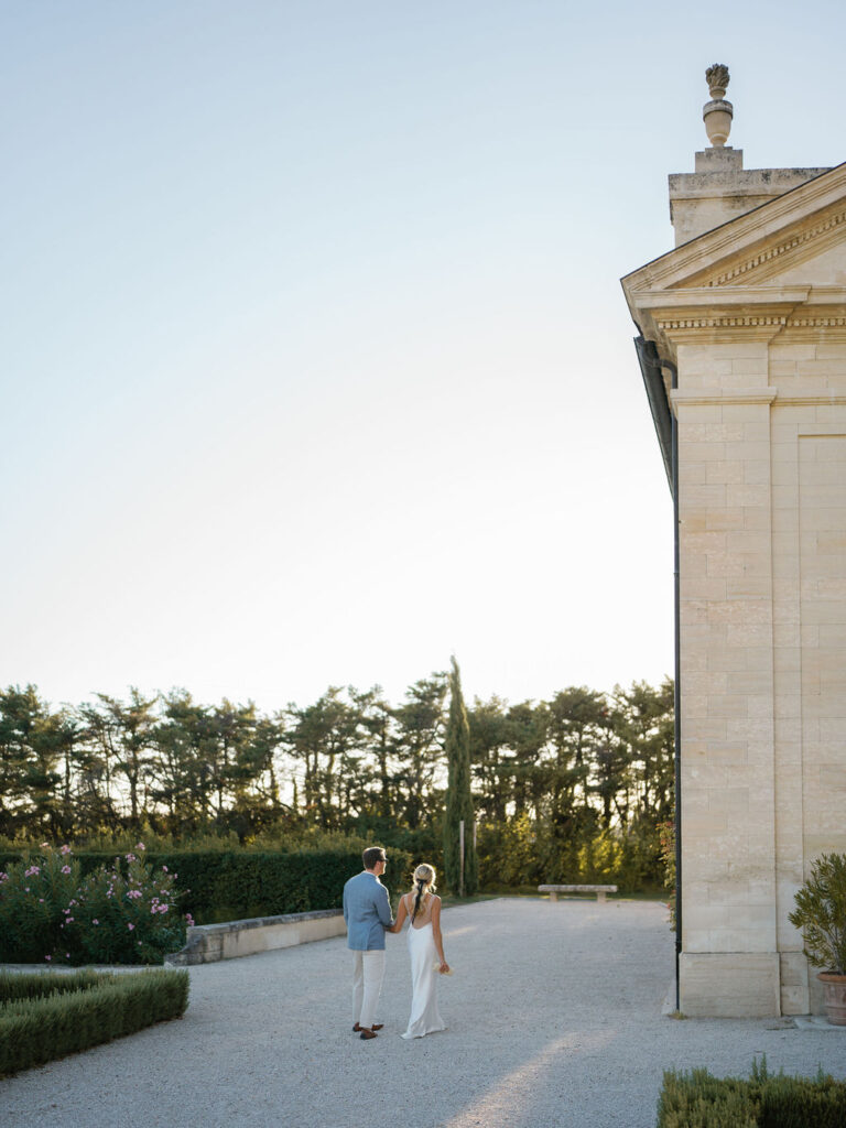 Bride and groom standing together near a historic chateau during a Provence wedding celebration.