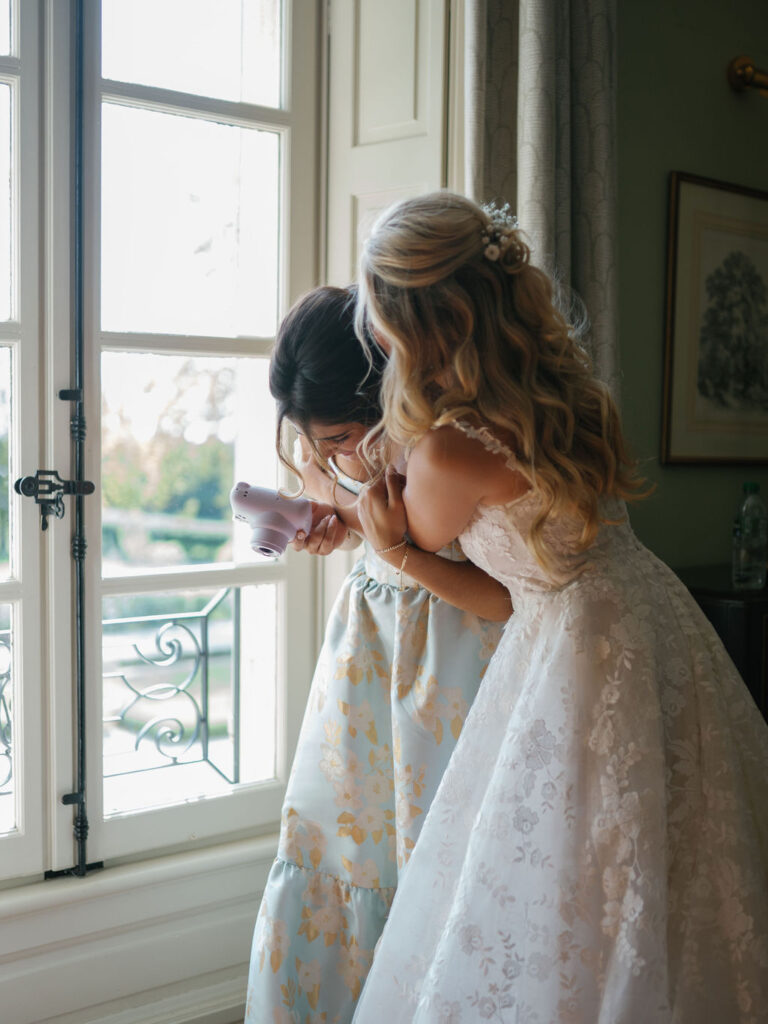Bride sharing a moment with bridesmaid near a window inside a Provence chateau.