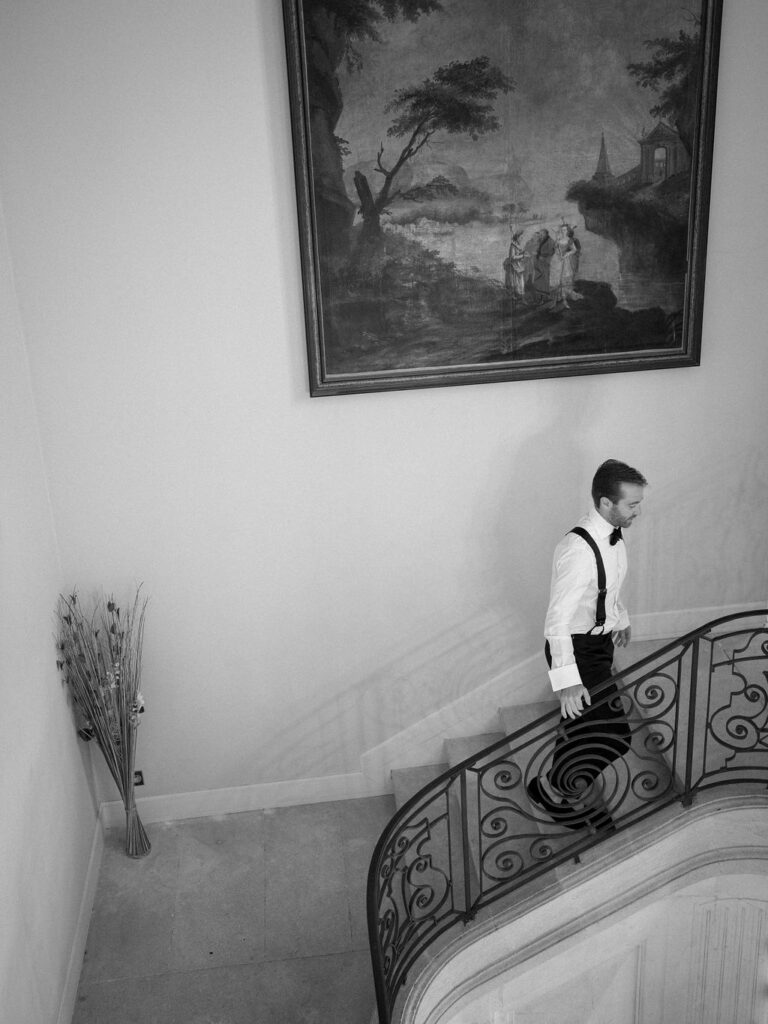 Groom walking along a curved staircase inside a Provence chateau.