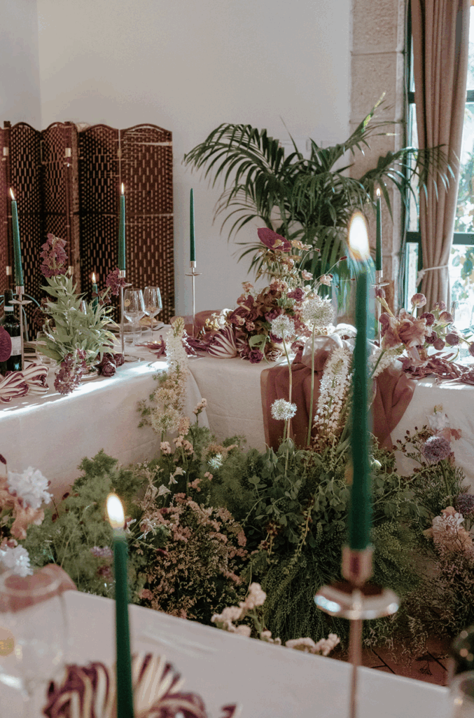 Candlelit reception table with layered florals and textures, contributing to a warm and immersive wedding guest experience.