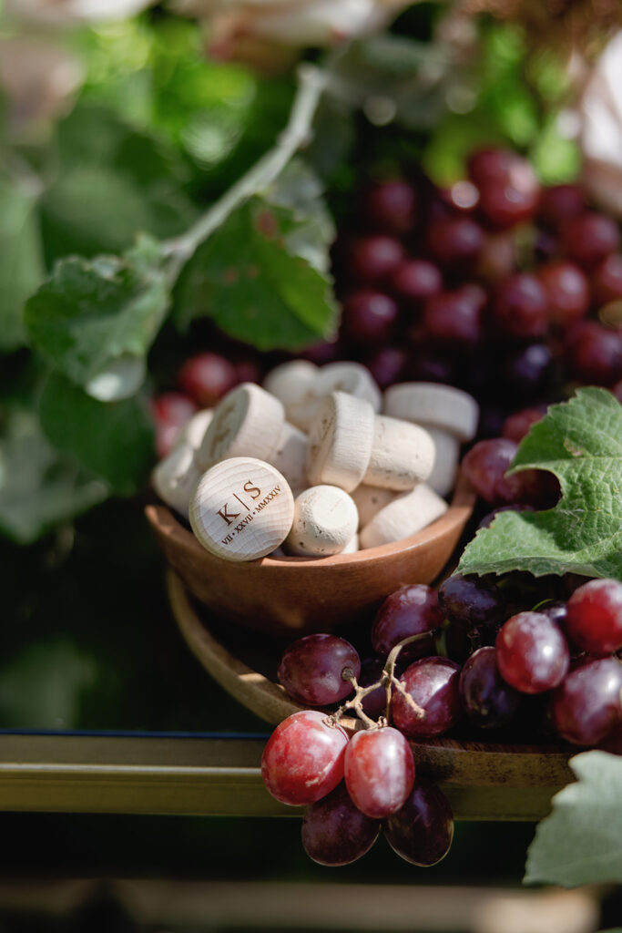 Artful wedding welcome display with grapes, wine corks, and floral accents at a Santa Barbara celebration