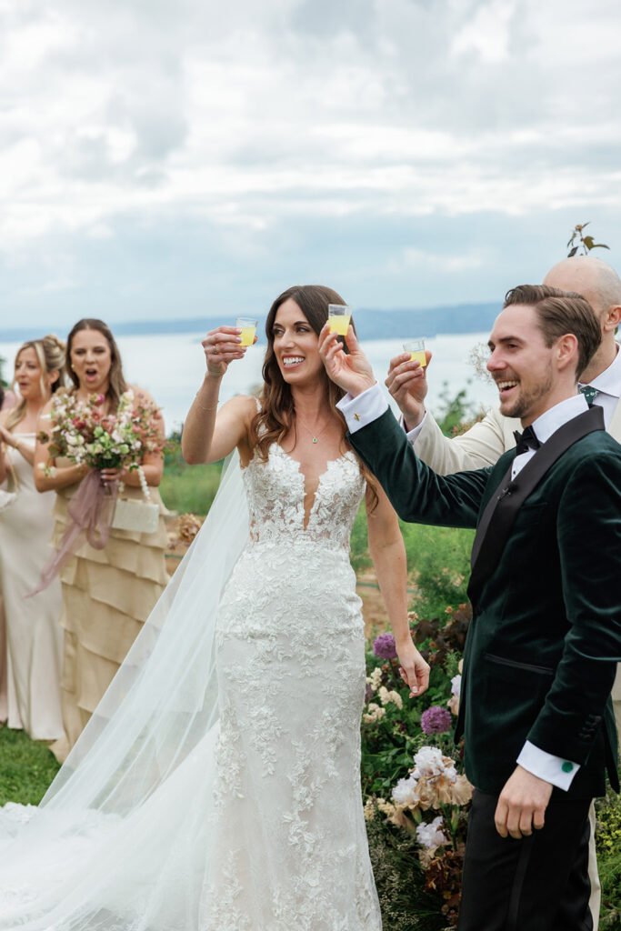 Bride and groom raising glasses with their wedding party outdoors, celebrating a joyful moment that enhances the overall wedding guest experience.