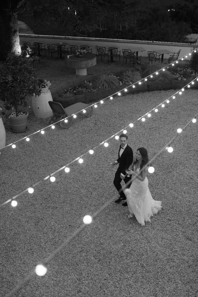 Overhead view of the couple walking beneath string lights in the evening, part of a thoughtfully paced wedding weekend experience.