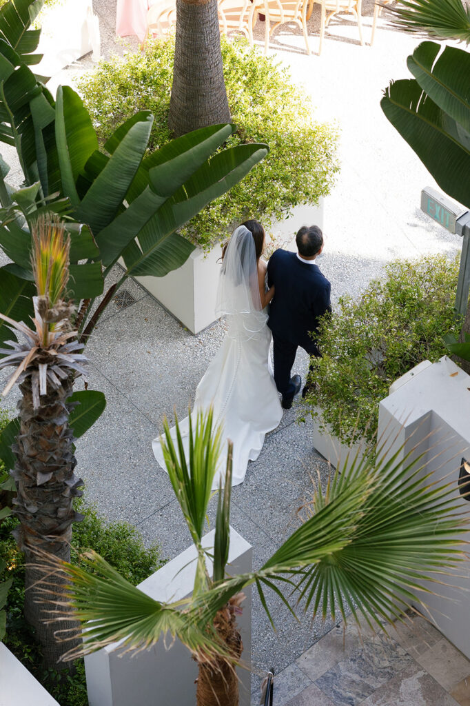 Overhead view of bride and father walking through a garden space highlighting thoughtful outdoor wedding design and guest flow.