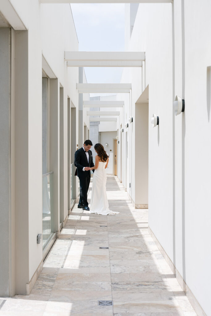 Bride and groom standing in a modern outdoor corridor as part of a refined luxury wedding design.