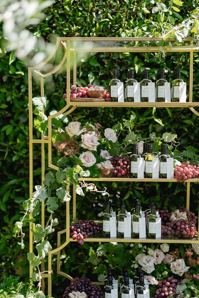 Curated wine and champagne display with fresh florals and grapes styled for an elevated wedding guest experience.