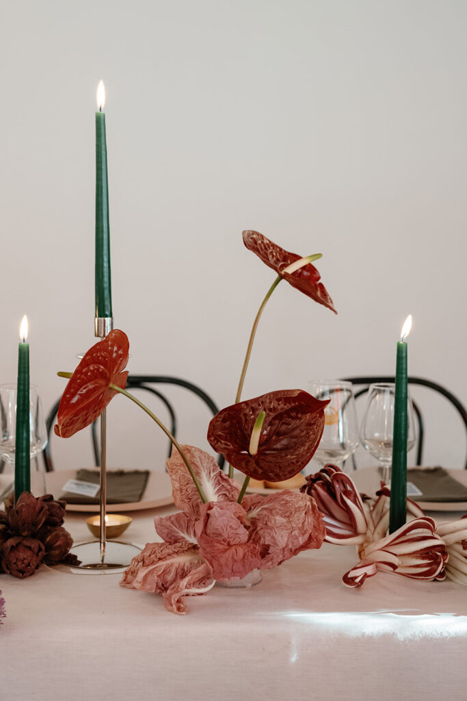 Editorial tablescape with candles and sculptural florals designed to elevate the wedding guest experience at dinner.