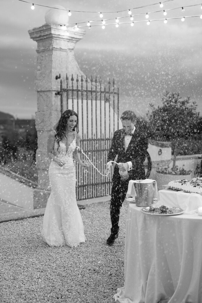 Black and white image of the couple serving cake to guests, capturing a shared moment within the wedding reception experience.