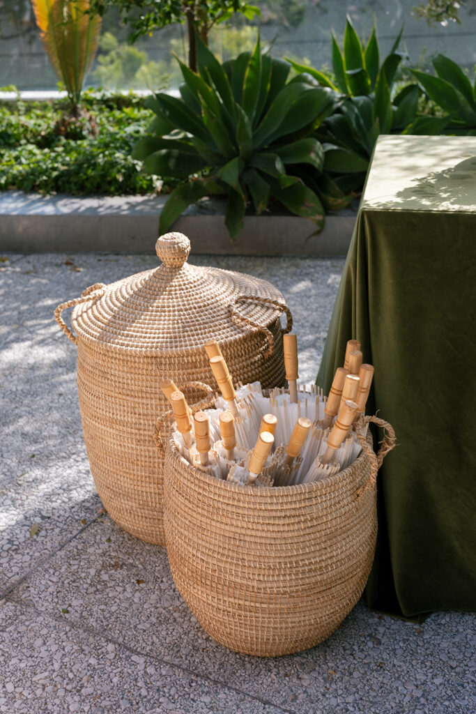Woven baskets with ceremony programs styled beside a table as part of a refined luxury wedding design.