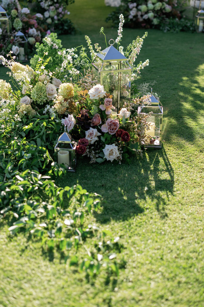 Garden floral installation with lanterns creating a refined coastal wedding atmosphere
