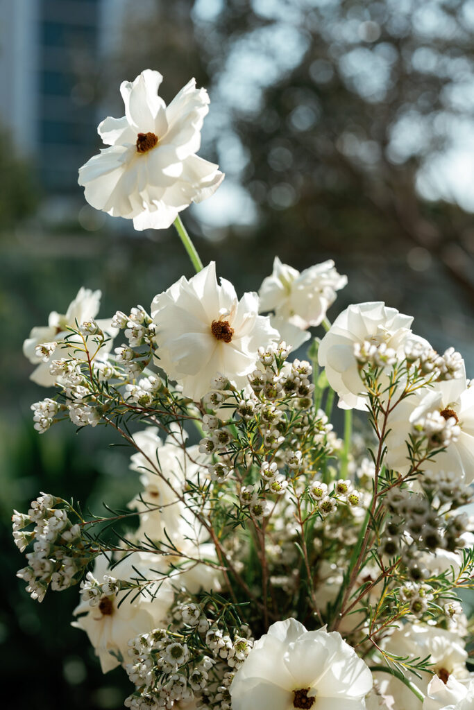 White floral arrangement styled outdoors with natural textures, reflecting luxury outdoor wedding design.