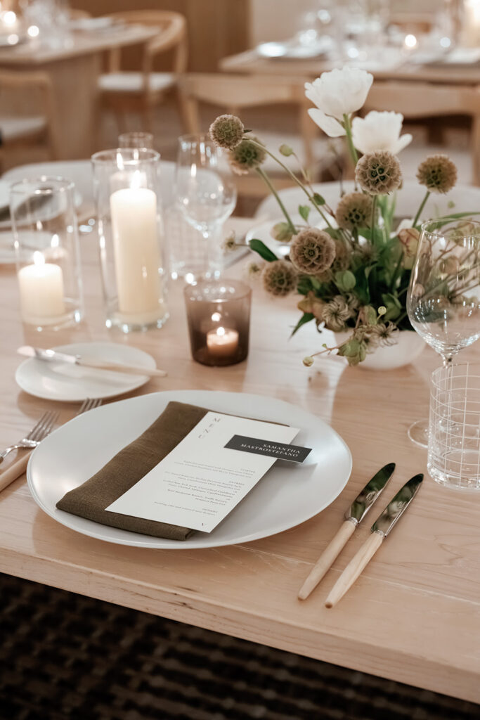 Wedding place setting with menu card, linen napkin, candles, and floral centerpiece, showcasing the intentional details couples receive with wedding planning.