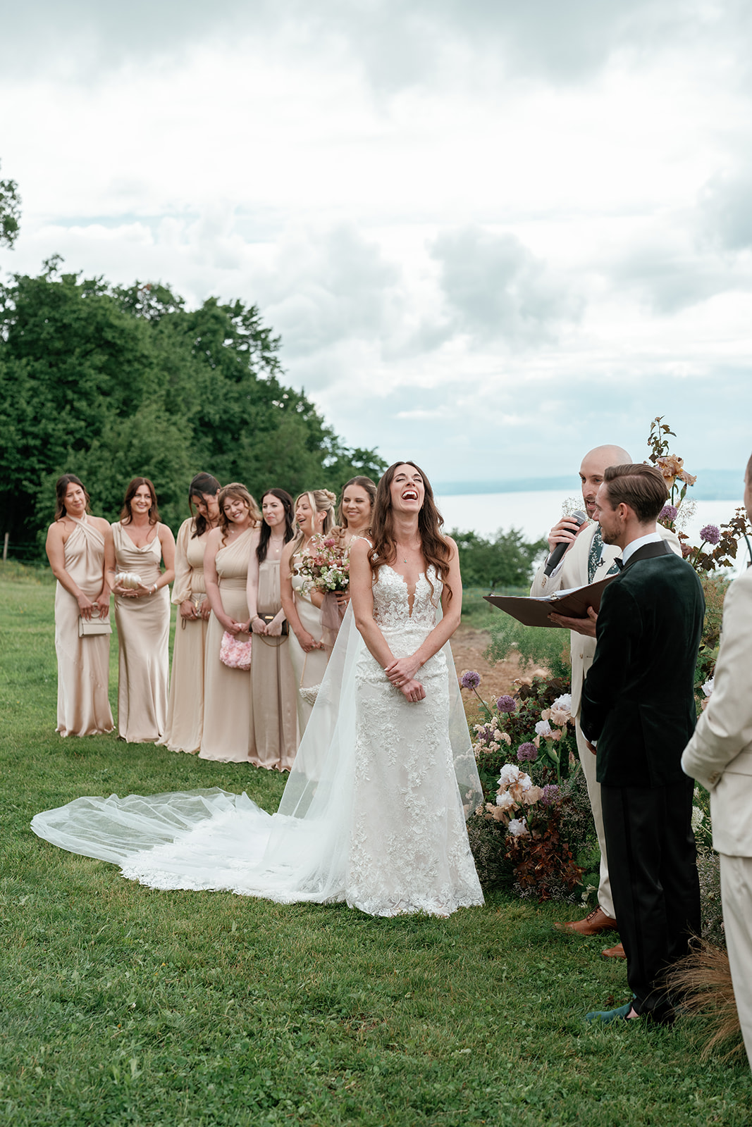 A bride laughs with pure joy during an outdoor unplugged ceremony, standing at the altar with her bridal party and a no phone wedding policy in place.