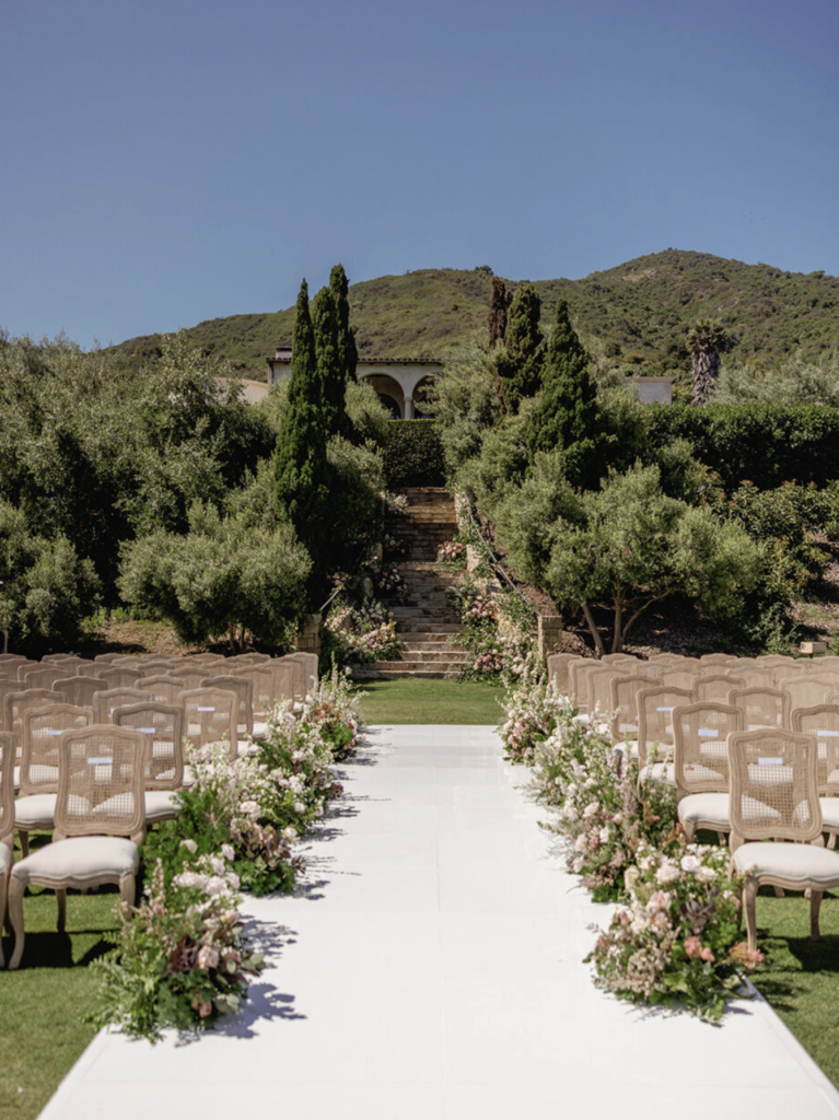 Outdoor wedding ceremony aisle with white chairs and floral arrangements at a Santa Barbara hillside venue